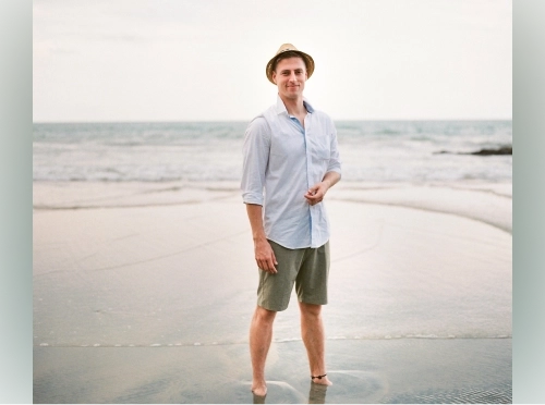 Smiling man with a hat wearing a light-blue shirt.