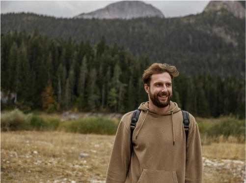 A smiling man with brown hair and beard in a hoodie